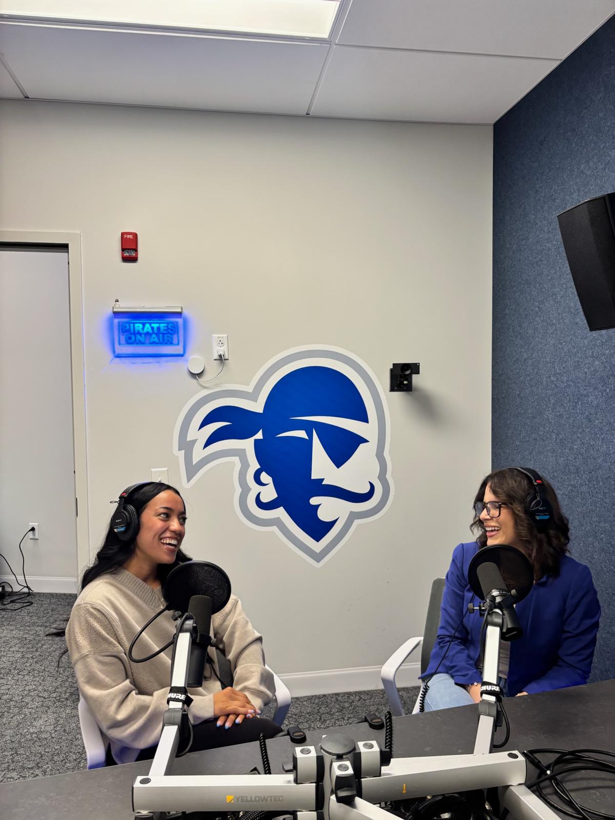 Jazzlyn laughing with a co-host in the Seton Hall Pirates On Air podcast studio